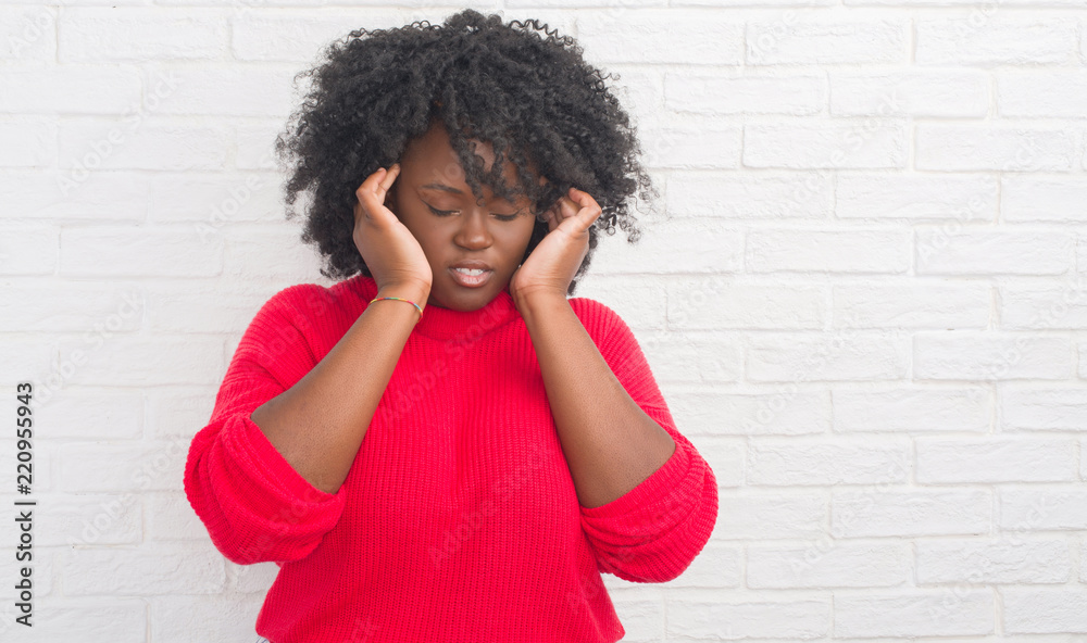 Young african american plus size woman over white brick wall with hand on head for pain in head because stress. Suffering migraine. Young african american plus size woman over white brick wall with hand on head for pain in head because stress. Suffering migraine.