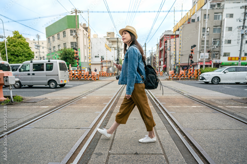 Fototapeta premium woman walking across the railroad holding phone