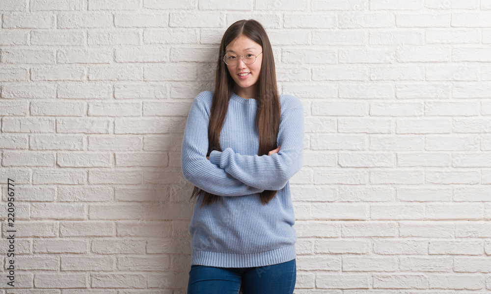 Young Chinise woman over white brick wall happy face smiling with crossed arms looking at the camera. Positive person. Young Chinise woman over white brick wall happy face smiling with crossed arms looking at the camera. Positive person.