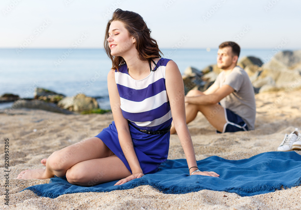 Fototapeta premium Girl sitting on the beach. Man on the background