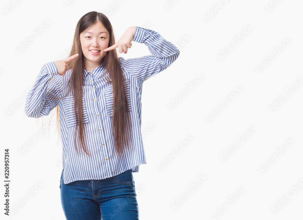 Young Chinese woman over isolated background smiling confident showing and pointing with fingers teeth and mouth. Health concept.