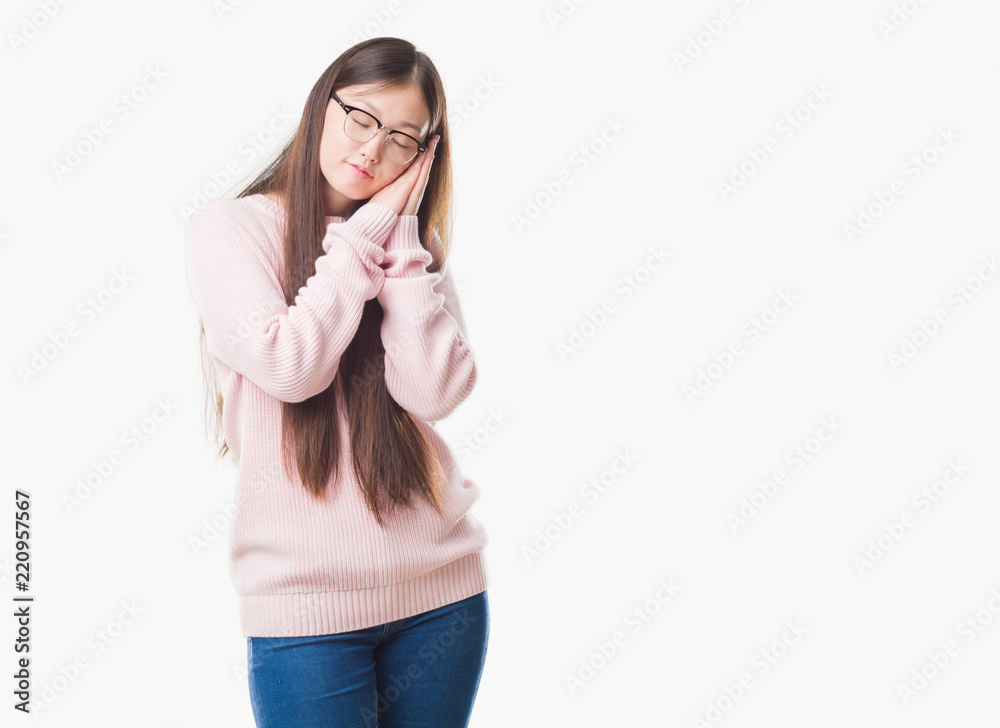 Young Chinese woman over isolated background wearing glasses sleeping tired dreaming and posing with hands together while smiling with closed eyes. Young Chinese woman over isolated background wearing glasses sleeping tired dreaming and posing with hands together while smiling with closed eyes.