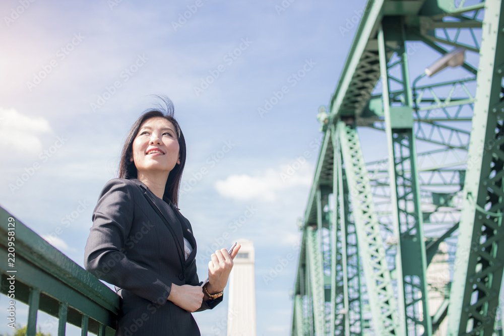 Portrait of business woman outside of building standing on old metal bridge. Confident female looking out with vision and hope