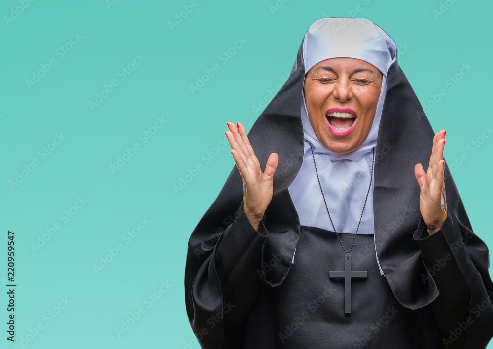 Middle age senior christian catholic nun woman over isolated background celebrating mad and crazy for success with arms raised and closed eyes screaming excited. Winner concept Middle age senior christian catholic nun woman over isolated background celebrating mad and crazy for success with arms raised and closed eyes screaming excited. Winner concept