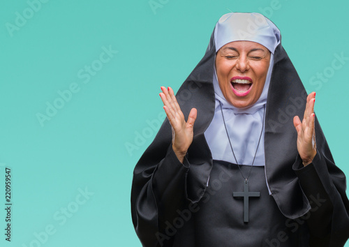 Middle age senior christian catholic nun woman over isolated background celebrating mad and crazy for success with arms raised and closed eyes screaming excited. Winner concept