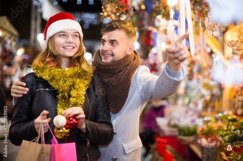 Couple in hat at Christmas Fair, man points to decorations