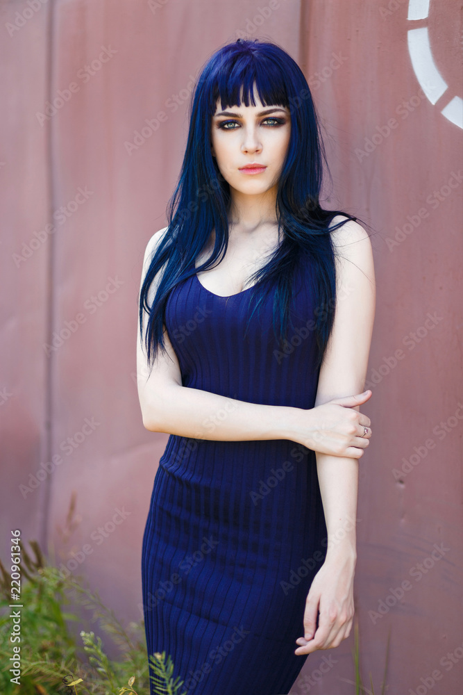 Young beautiful girl with perfect make-up, wearing a elegant blue dress, posing outdoor.