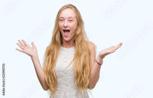 Blonde teenager woman very happy and excited, winner expression celebrating victory screaming with big smile and raised hands