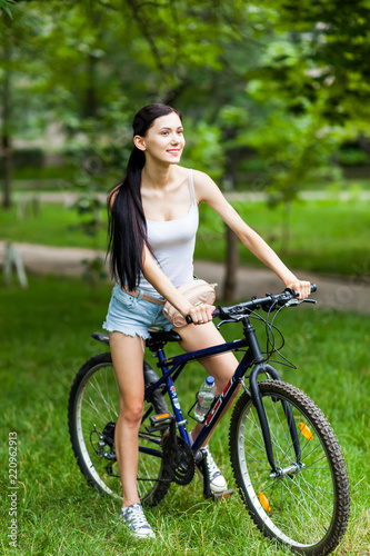 Teen girl with bicycle in a park.