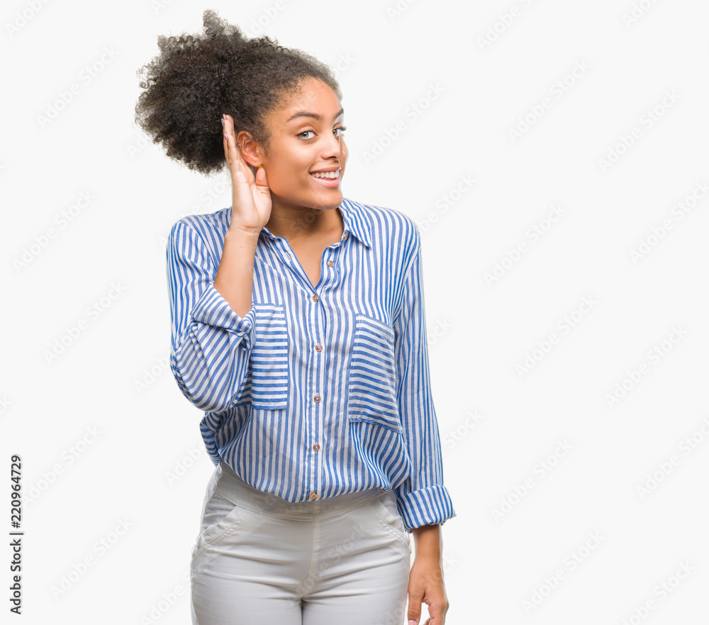 Young afro american woman over isolated background smiling with hand over ear listening an hearing to rumor or gossip. Deafness concept. Young afro american woman over isolated background smiling with hand over ear listening an hearing to rumor or gossip. Deafness concept.