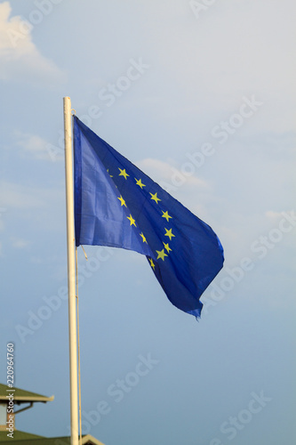 European Union flag on a blue sky with clouds background