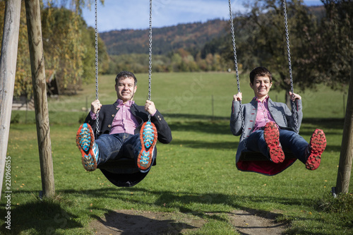 Youn couple enjoying an autumn sun on the swing, having fun photo