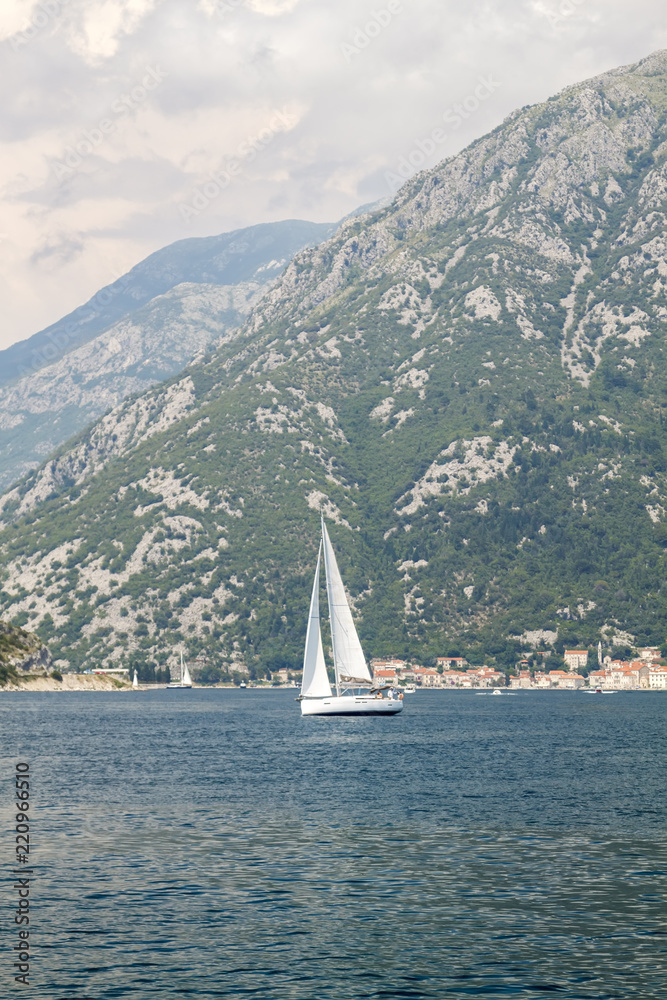 spectacular views of the boat in the middle of the Bay of Kotor and the city of Perast at the foot of the mountain behind