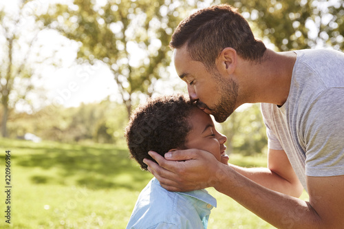 Close Up Of Father Kissing Son In Park photo