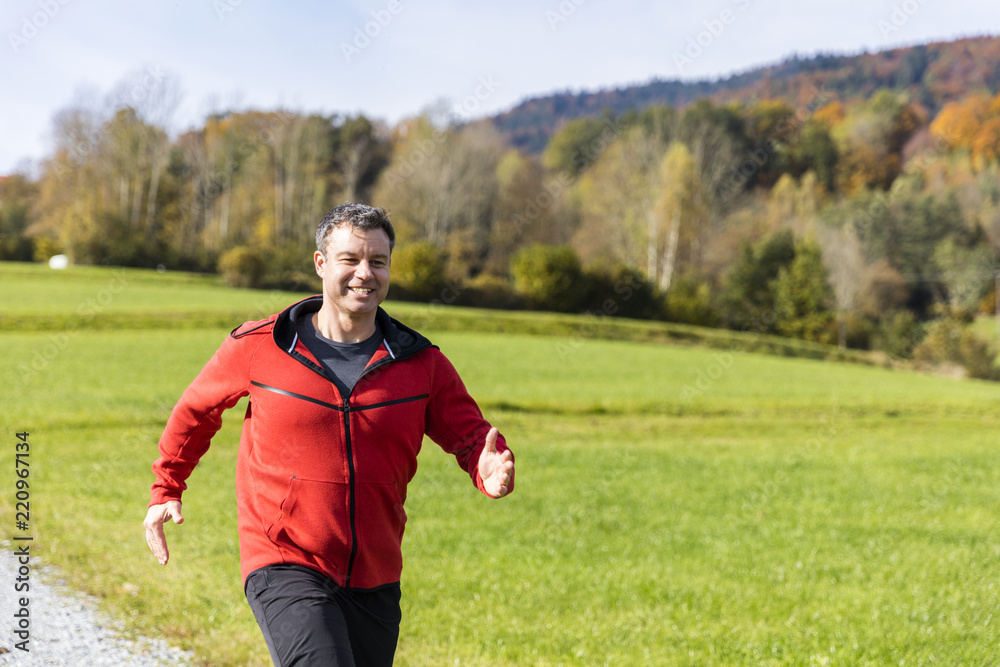 A man running outdoors on the sunny autumn day in the countryside of Bavarian National Forest Park A man running outdoors on the sunny autumn day in the countryside of Bavarian National Forest Park