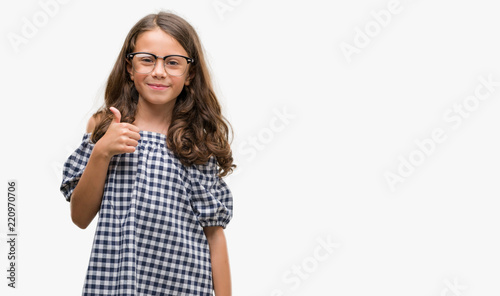 Brunette hispanic girl wearing glasses happy with big smile doing ok sign, thumb up with fingers, excellent sign