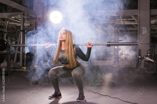 sport, fitness, training and happiness concept - sporty woman with barbell in gym