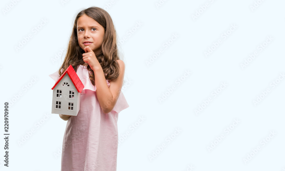 Brunette hispanic girl holding little house serious face thinking about question, very confused idea Brunette hispanic girl holding little house serious face thinking about question, very confused idea