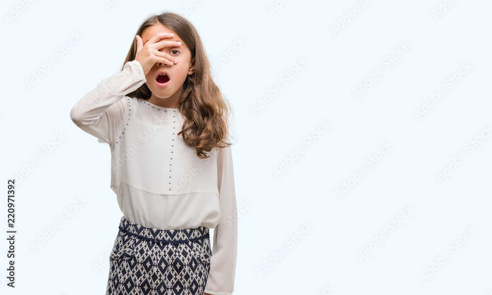 Brunette hispanic girl peeking in shock covering face and eyes with hand, looking through fingers with embarrassed expression. Brunette hispanic girl peeking in shock covering face and eyes with hand, looking through fingers with embarrassed expression.