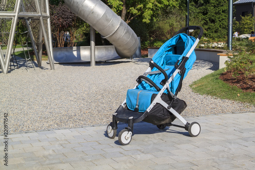 empty stroller stands near a modern playground with a large metal slide