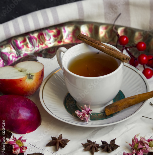 A cup of tea with red apples and cinnamon