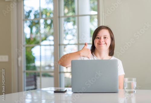 Down syndrome woman at home using computer laptop happy with big smile doing ok sign, thumb up with fingers, excellent sign Free Download Down syndrome woman at home using computer laptop happy with big smile doing ok sign, thumb up with fingers, excellent sign - GFXLoad