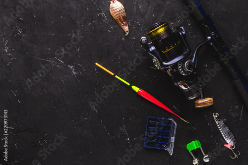 Fishing tackle on a black background. Fishing accessories. Top view, copy space