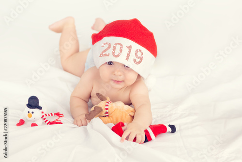 Xmas card with cute baby girl with santa hat on beige airy briht background with copy space photo