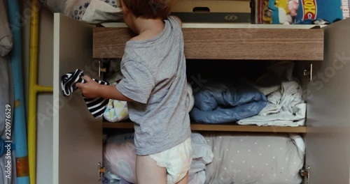 Baby boy at closet. Kid looks in the closet things