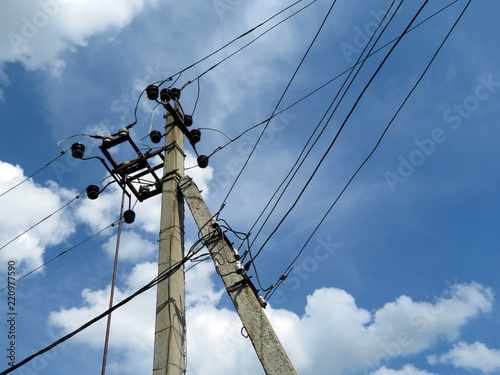 Power line support against blue sky with white clouds. Power pole with electrical wires and capacitors