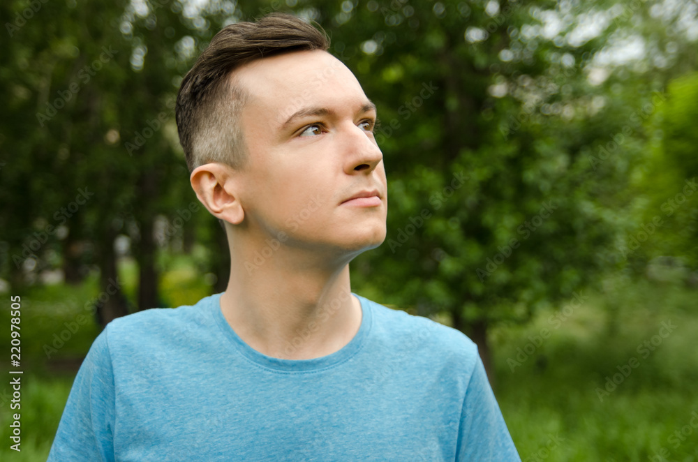 Portrait of young guy looking up, on a green grass and trees background. Portrait of young guy looking up, on a green grass and trees background.