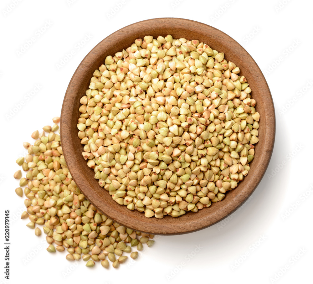 uncooked buckwheat in the wooden plate, isolated on the white background, top view uncooked buckwheat in the wooden plate, isolated on the white background, top view