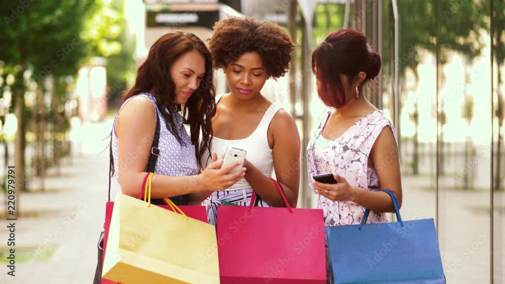 sale, consumerism and people concept - happy young women with smartphones and shopping bags on city street sale, consumerism and people concept - happy young women with smartphones and shopping bags on city street