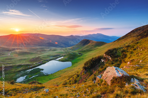 Fototapeta Naklejka Na Ścianę i Meble -  Breathtaking sunrise landscape - the  lake Dogyaska in high mountains of Svydovets mountain chain system. Green, yellow and lilac colors in nature. Fantastic valley lit with morning sun, terrific view