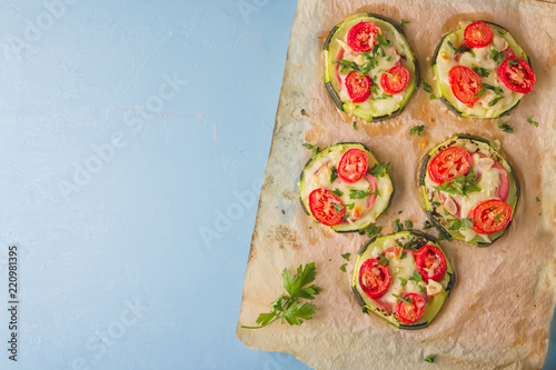 Zucchini small round pizza with pepperoni and tomatoes.