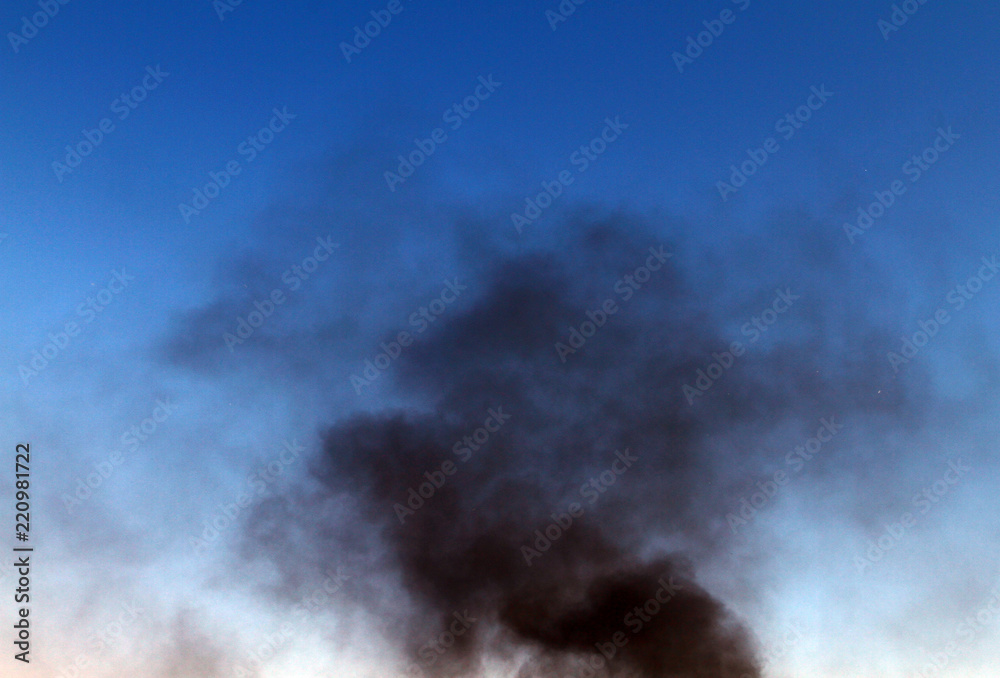 dark smoke pillar on the blue sky background.