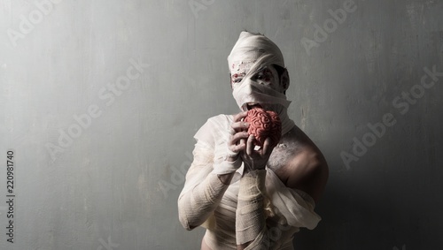 Leinwand Poster Terrorific mummy eating a brain on textured wall background