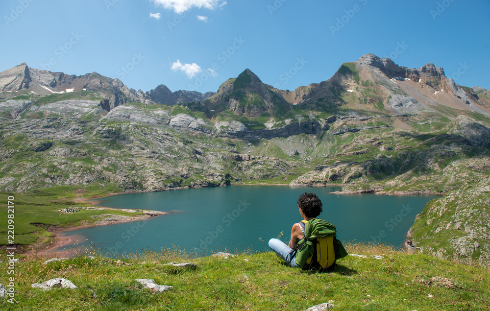 woman hiker looking at Lake Estaens in the Pyrenees mountains woman hiker looking at Lake Estaens in the Pyrenees mountains