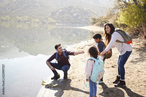 Parents with young children exploring beside a mountain lake