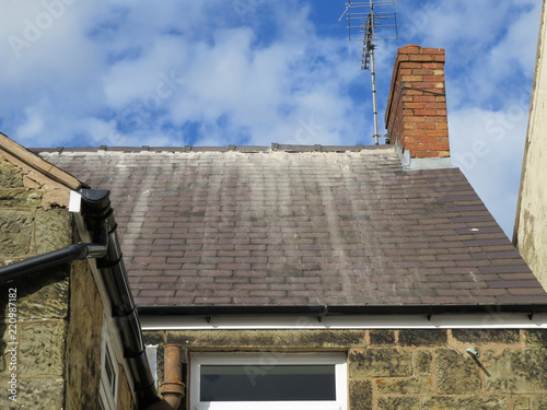 Shoddy roofing work by cowboy builder. Results of rouge worker posing as skilled tradesman. Badly pointed ridge tiles on slate roof, mortar running down tiles.