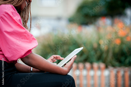 African girl using tablet at city street, close up on finger touching screen