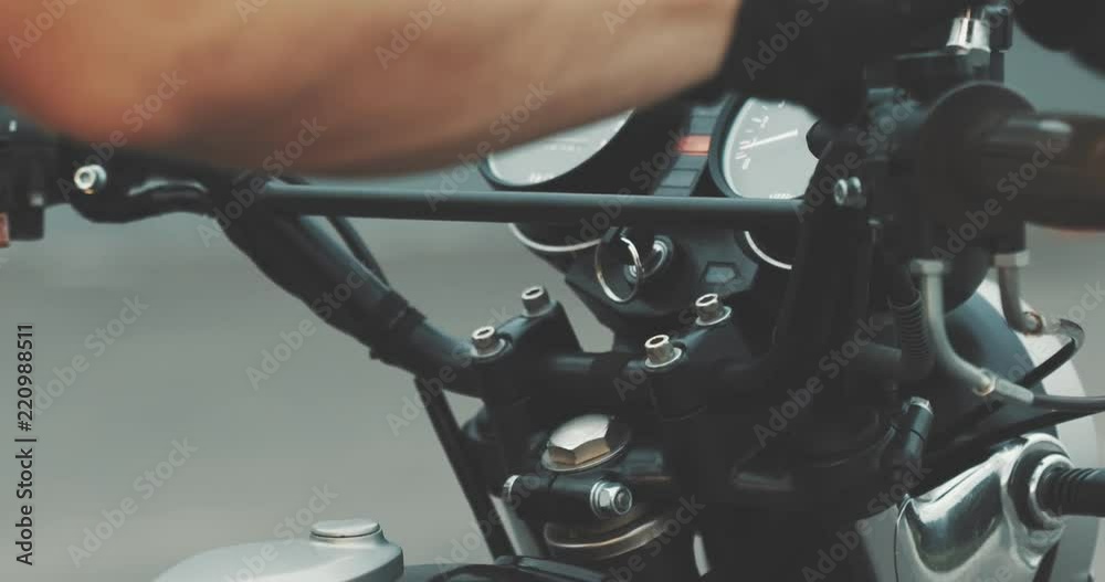 Motorbike handle grips. Close up the hand of the motorcyclist holds the trottle and pushes the brake lever. The biker inserts the key into the ignition lock and turns the bike. Motorbike handle grips. Close up the hand of the motorcyclist holds the trottle and pushes the brake lever. The biker inserts the key into the ignition lock and turns the bike.