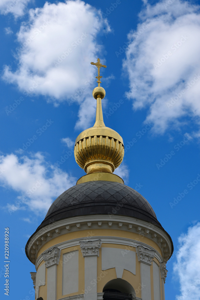 Moscow. The dome of the Orthodox church, covered with gold against the blue sky and white clouds.