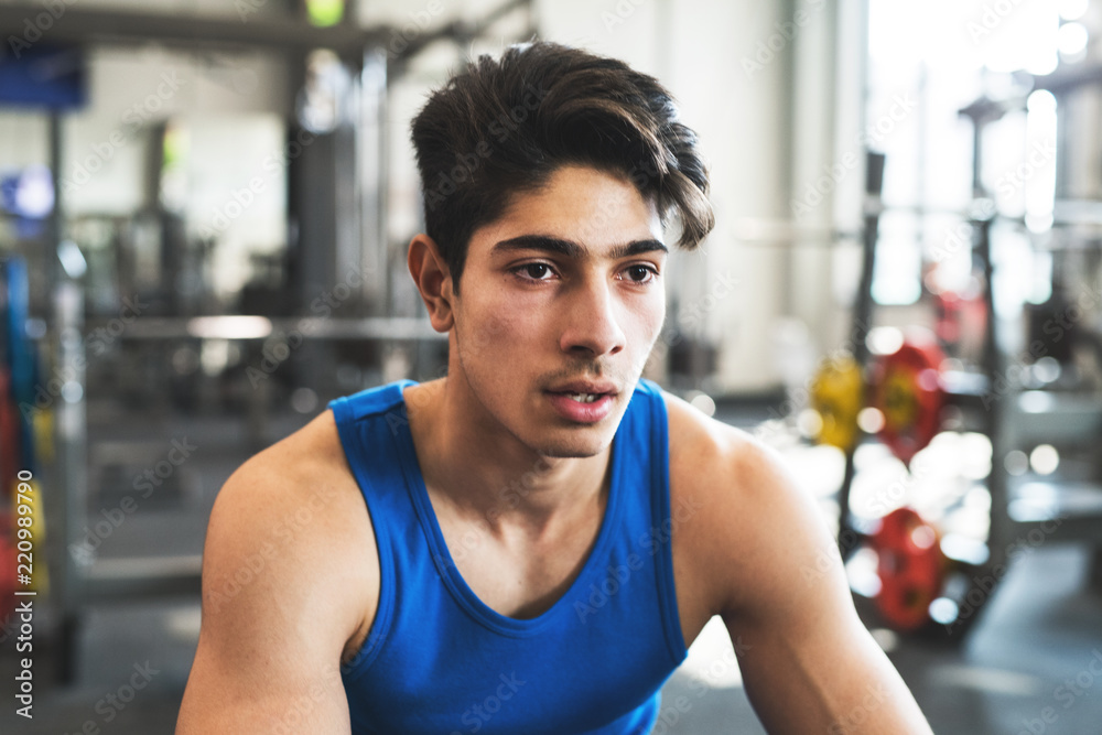 A close up of a young man in crossfit gym, resting after an exercise. A close up of a young man in crossfit gym, resting after an exercise.