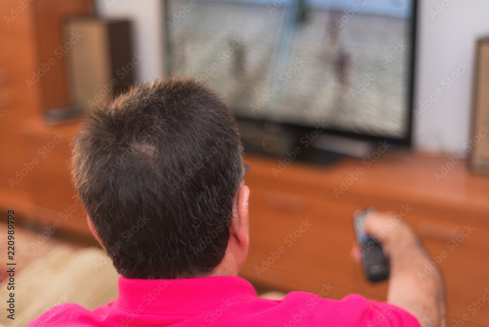 Back view of senior man watching tv holding remote control Back view of senior man watching tv holding remote control