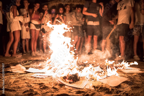 Hoguera de San Juan en la playa con llamas, fuego y personas photo