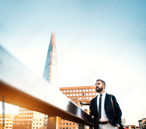 Hipster businessman with coffee standing on the bridge in London. Copy space.