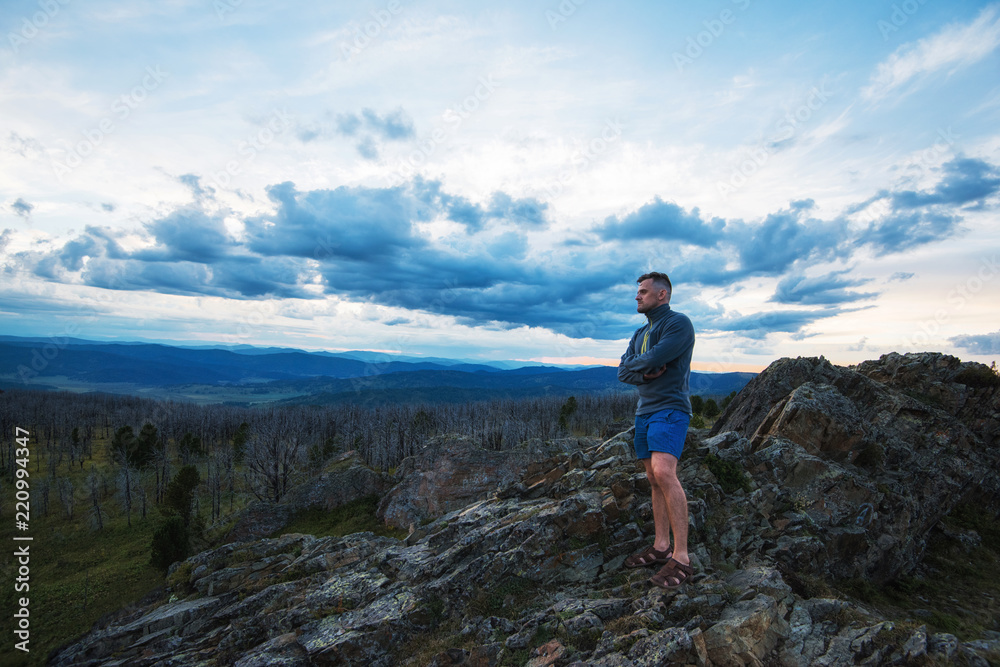 Naklejka premium Travel, freedom and tourism concept - man standing on top of cliff in summer beauty evening in Altai mountains
