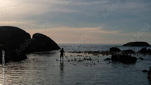 Paddle boarder silouette at sunset on calm sea