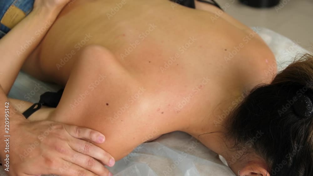 Manual therapist massaging a young woman lying on a massage table, pushing on the back. Young female enjoying professional spine and back treatment. shoulder joint Manual therapist massaging a young woman lying on a massage table, pushing on the back. Young female enjoying professional spine and back treatment. shoulder joint